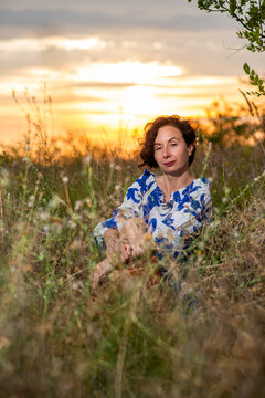Woman Sitting in Meadow at Sunset
