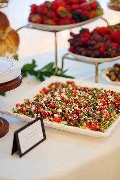 tabbouleh salad arranged on a porcelain plate at a banquet setting with bread rolls and fruit platt.
