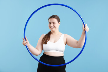 Overweight woman with hula hoop on light blue background © New Africa