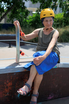 Elderly woman rides skateboard in park as she enjoys a sunny afternoon