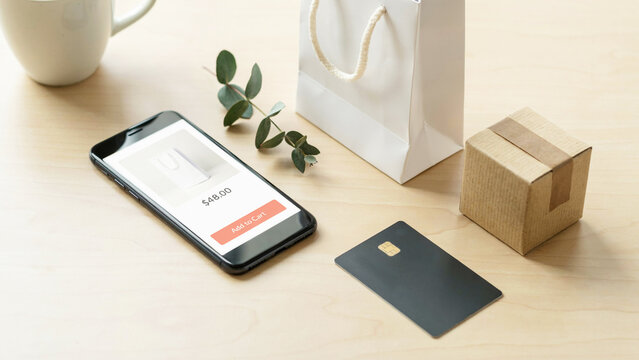 Online shopping payment process with smartphone showing payment confirmation and credit card on wooden surface