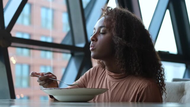 Such delicious tasty filling food. Close-up of a curly-haired beautiful woman tasting food in a new restaurant.