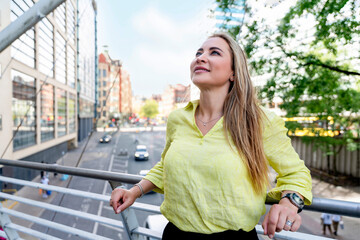 Fototapeta premium Woman enjoys the view on a city balcony on a sunny day while looking up and smiling