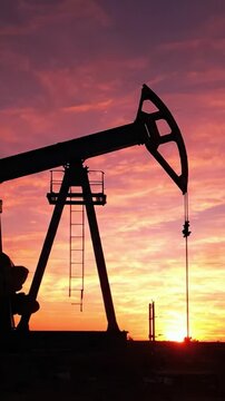Silhouetted Oil Pump Jack Against a Vibrant Sunset Sky, Capturing the Essence of Energy Production in a Visually Striking Scene of Nature and Industry