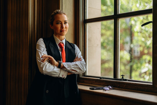 Business professional stands by window in office during daytime in urban area