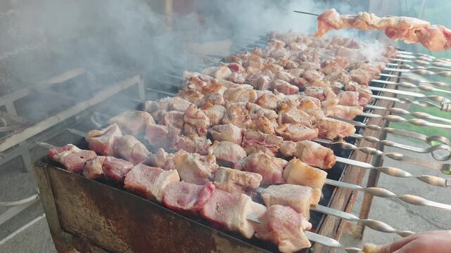 Grilling marinated meat skewers over hot coals with smoke rising