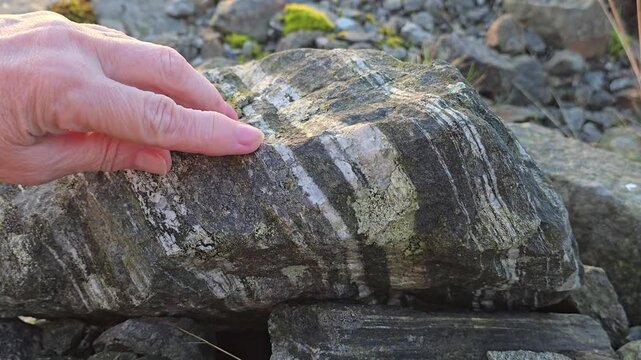 A hand strokes the patterns on a granite stone. Norway, Alver. August