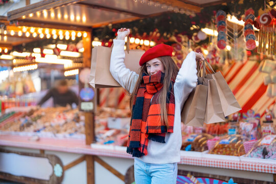 Woman enjoys shopping at a festive market with brown bags in her hands during winter time
