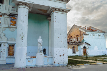 Naklejka premium Damaged heritage building with shrapnel marks on white columns and standing statue after military shelling during armed conflict