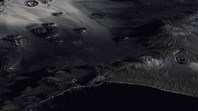 A view of the surface of the moon displays many craters and geological features. The dark terrain highlights the unique shapes of these craters. This scene captures the moons surface on a clear day.