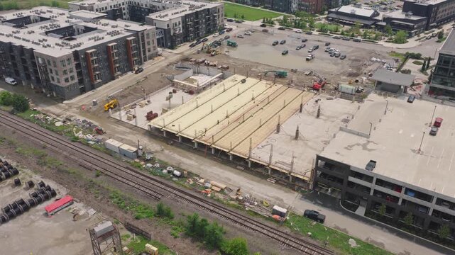 Drone aerial of new building construction of parking garage structure being structured and built by contractor crew at modern apartment complex for rental property tenants to park cars and vehicles 4k