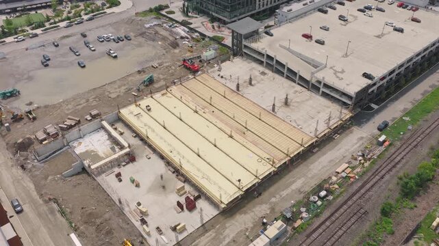Drone aerial of new building construction of parking garage structure being structured and built by contractor crew at modern apartment complex for rental property tenants to park cars and vehicles 4k