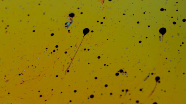 Abstract Macro Shot of Liquid Fluid Dynamics with Swirling Black Oil Droplets on Yellow Background