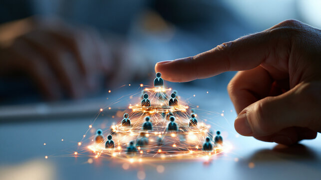 Hand shown placing the top layer of a glowing pyramid structure connected to people icons on bright clean background close up composition representing organizational structure