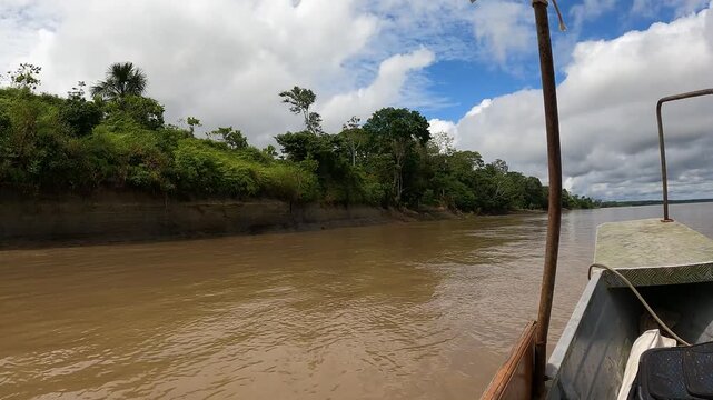 Small motorboat with two men navigating the Amazon River through the rainforest