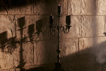 Obraz premium Antique candelabra with lit black candles casting shadows on a stone wall
