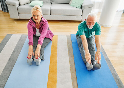 Senior couple exercise stretching or doing yoga at home, health care and active seniors concept
