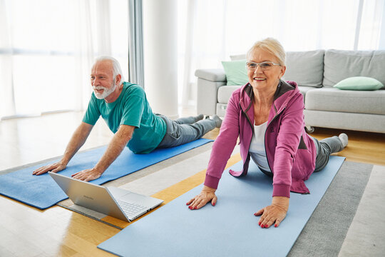 Senior couple exercise stretching yoga using laptop online instructions at home health care
