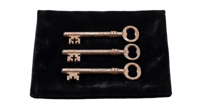 Three antique skeleton keys arranged on a black velvet surface
