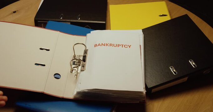 Person opens an office binder and reveals a Bankruptcy document. Ideal for business failure, financial crisis, insolvency and company debt.