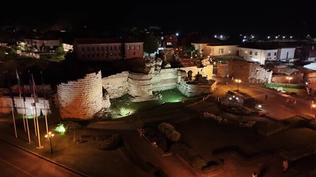 Aerial 4K night view of the ancient fortress wall and ruins at the entrance of Old Town Nesebar, Bulgaria