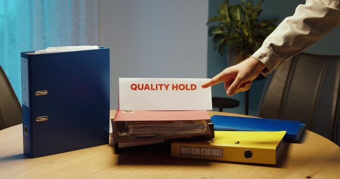 Worker placing a Quality Hold sign to indicate that documents and materials are blocked from further use pending quality review.