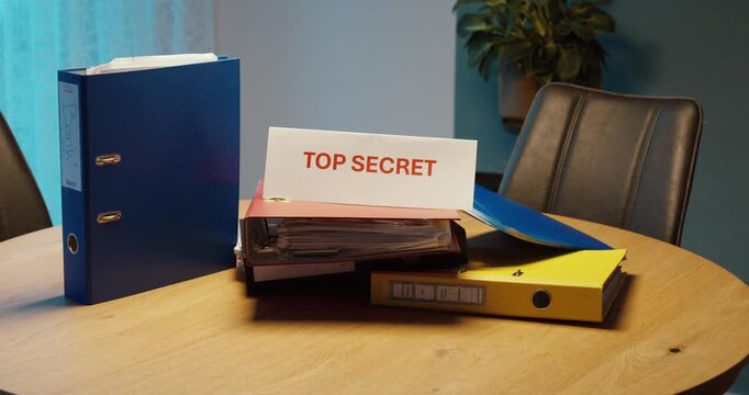 Person placing a Top Secret sign on a stack of office files. Ideal for confidential information, classified documents, privacy and data security.
