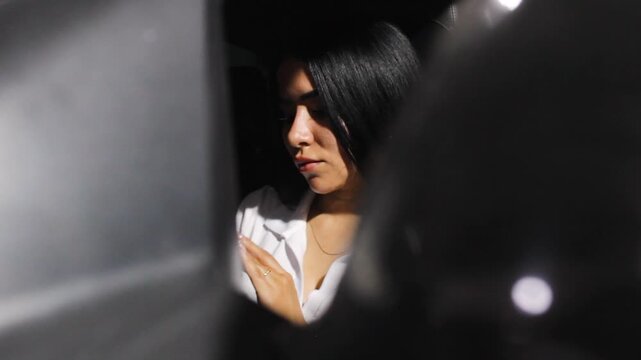 Portrait of a Hispanic woman sending a voice message on a cell phone inside her car in Neiva, Huila, Colombia. Concept of businesswoman and technology