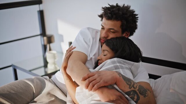 Gentle couple cuddling bedding closeup. Affectionate lovers embracing on bed