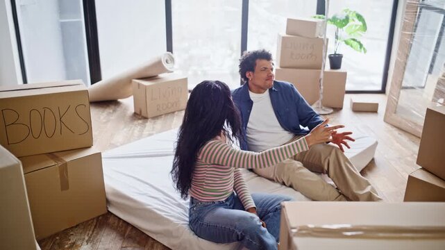 Multiracial couple enjoying relocate sitting floor in purchased house closeup