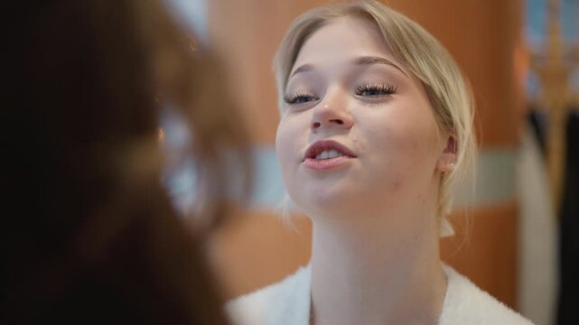 Close portrait of young woman speaking to someone off-frame with animated engaged expression, head tilted back slightly, mouth open, warm indoor light, soft blurred background and casual attire