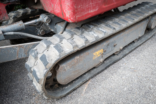Detailed view of a mechanical digger and excavator showing its work rubber tracks. The hydraulic piston for the shovel arm can be seen on the left.