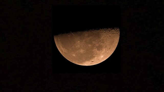 Detailed half moon moving across the dark night sky with visible surface craters and warm golden glow