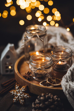 Aromatic christmas handmade candle with the sweet scent of gingerbread cookies. Cozy holiday home atmosphere, aromatherapy. Interior composition with burning candles, anise, cinnamon, pine cones