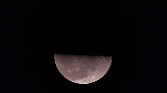 Close up view of detailed half moon moving across dark night sky