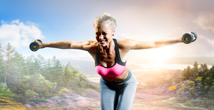 Fitness. A fit girl doing fitness exercises outdoors. An athletic woman working out. Photo of an athletic fitness model working out with dumbbells outdoors.