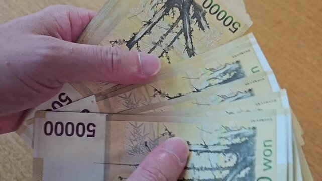 A scene of counting several 50,000-won bills by hand on a Korean banknote