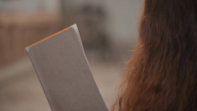 Tight shoulder-level close-up of person holding closed textured notebook or journal in right hand with slight downward tilt and steady grip, suggesting reading, quiet contemplation, and calm