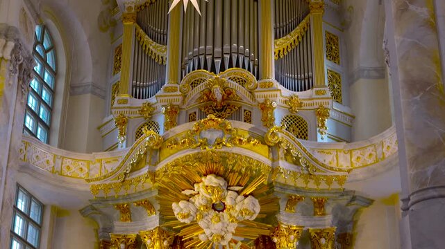 Baroque pipe organ in ornate european cathedral. Majestic interior of a historic christian church, showing an opulent golden pipe organ, lavish gilded sculptures, and detailed frescoes on the ceiling