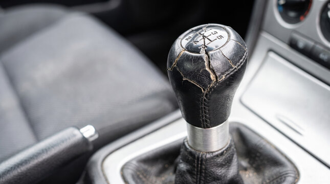 Close-up of a cracked gear shift knob in a car interior. Manual transmission vehicle detail.