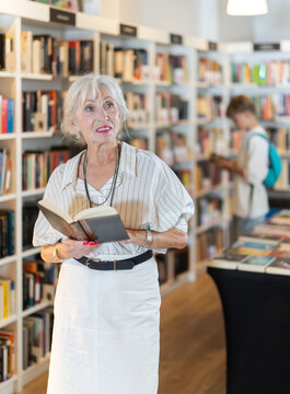 Senior female reader explores aisles of bookstore, looking for new title to enjoy
