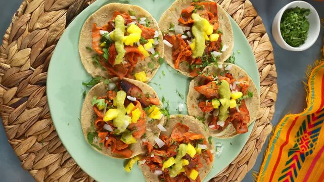 Mexican street food flat lay of tacos al pastor with salsa verde, chopped cilantro, and limes