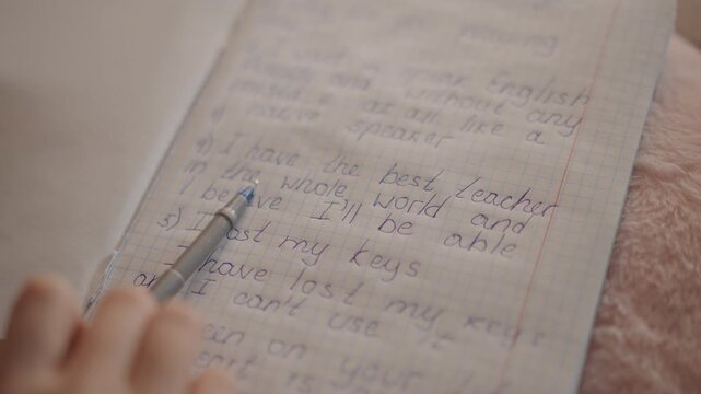 Low viewpoint of hand holding pencil and pointing toward handwritten equations and bullet notes on lined notebook page, showing active review, correction, and careful study during focused desk work