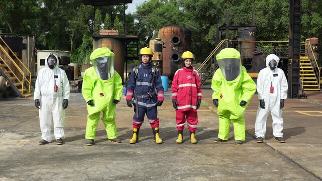 Hazmat firefighter in protective suit during chemical spill emergency response, industrial refinery yard decontamination drill, chemical plant training, safety exercise, rescue team readiness