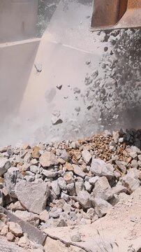Unloading of stone from the truck to the stone crushing machine at open pit mining and processing plant for crushed stone. Concepts of industry and building materials, sand and gravel