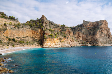 Fototapeta premium The ocean view from the wooden railing reveals rocky cliffs and calm water. A majestic cliffside view drenched in sunlight. The concept is nature, enjoyment.
