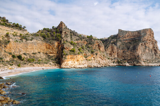 The ocean view from the wooden railing reveals rocky cliffs and calm water. A majestic cliffside view drenched in sunlight. The concept is nature, enjoyment.