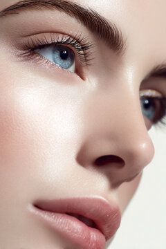 Close up of a woman's face, focusing on her perfect skin, blue eye, and delicate makeup, emphasizing beauty and care
