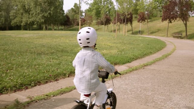Child riding bike learning with mother in park