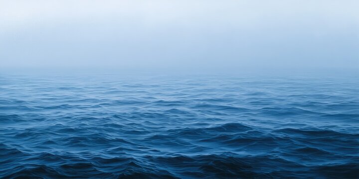 Deep blue ocean waves merge into a soft, misty horizon